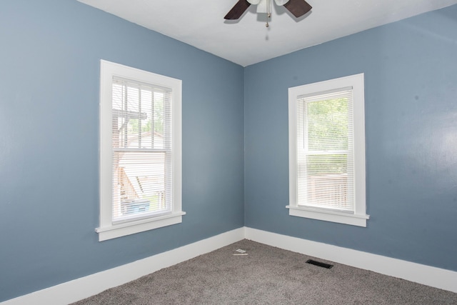 unfurnished room featuring plenty of natural light, carpet floors, a ceiling fan, and baseboards
