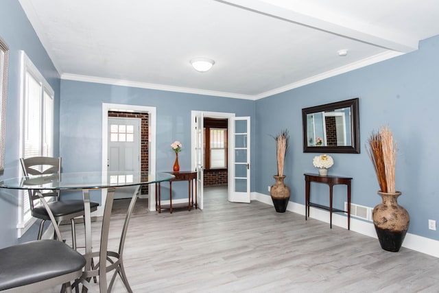 dining area with light wood-style flooring, baseboards, and ornamental molding