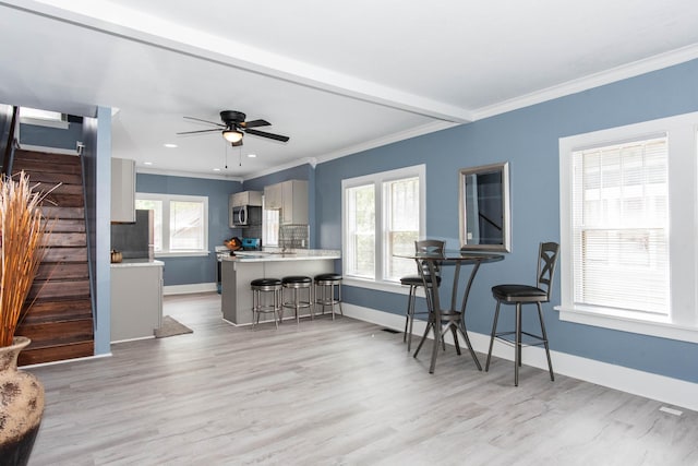 living room with healthy amount of natural light, crown molding, light wood-style flooring, baseboards, and recessed lighting