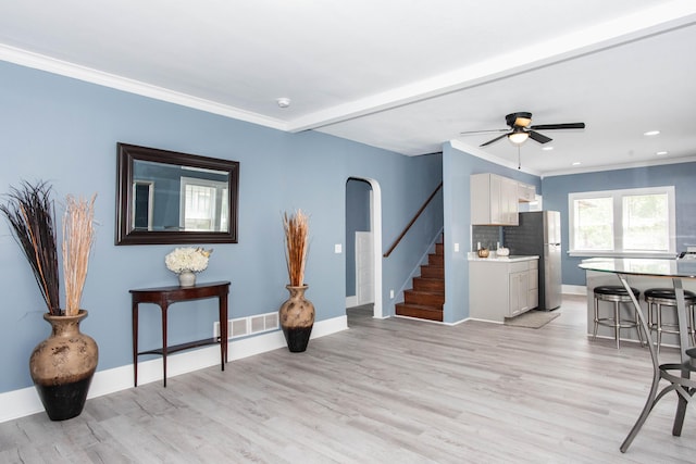 living room featuring stairs, ornamental molding, arched walkways, light wood-type flooring, and recessed lighting
