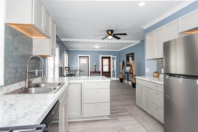 kitchen with freestanding refrigerator, a sink, a peninsula, a ceiling fan, and light wood finished floors
