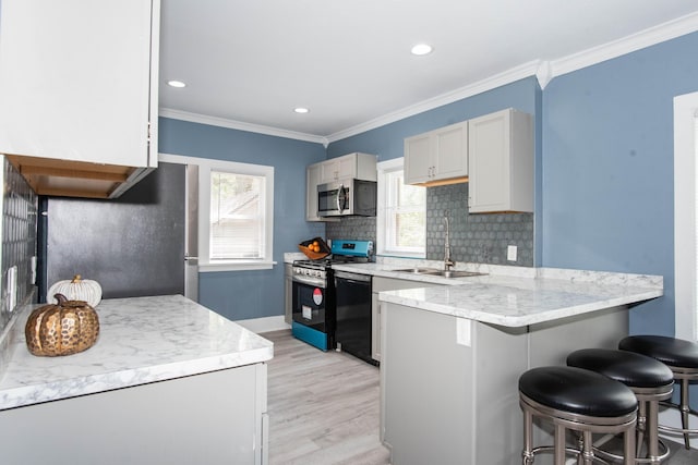 kitchen featuring appliances with stainless steel finishes, a peninsula, a sink, healthy amount of natural light, and recessed lighting