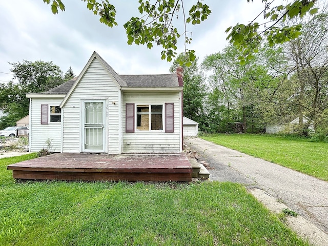 back of house with a chimney, a lawn, roof with shingles, a wooden deck, and a garage