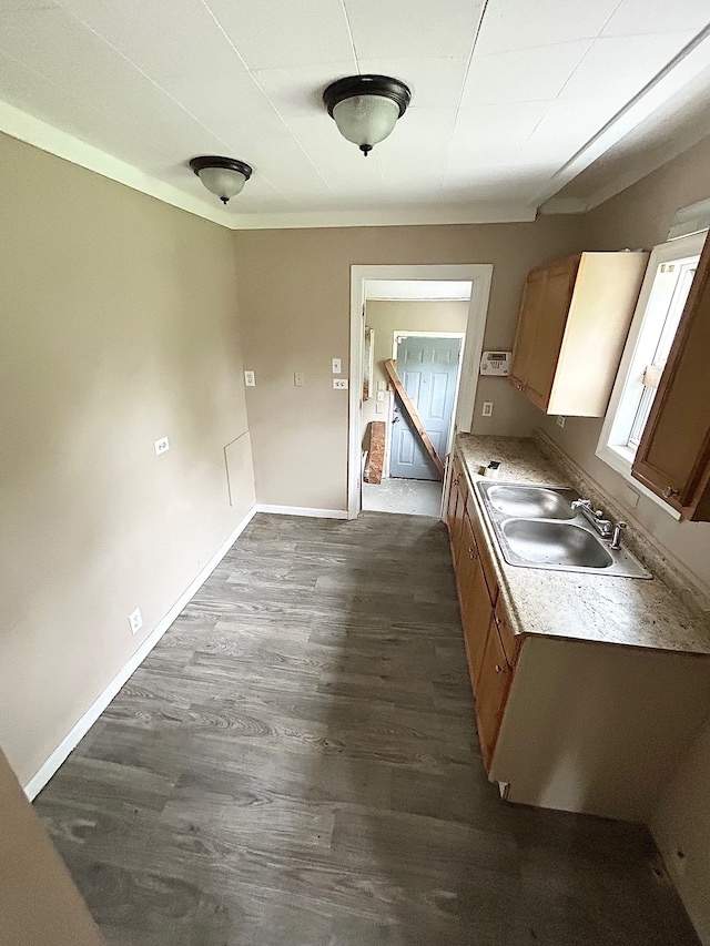 kitchen with a sink, dark wood-style floors, light countertops, baseboards, and brown cabinetry