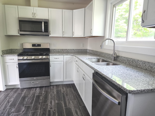 1301 Andrea St, Ypsilanti, MI 48198 - kitchen with appliances with stainless steel finishes, a sink, white cabinetry, light stone counters, and wood tiled floors