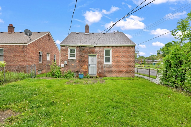 rear view of house featuring brick siding, a chimney, and roof with shingles