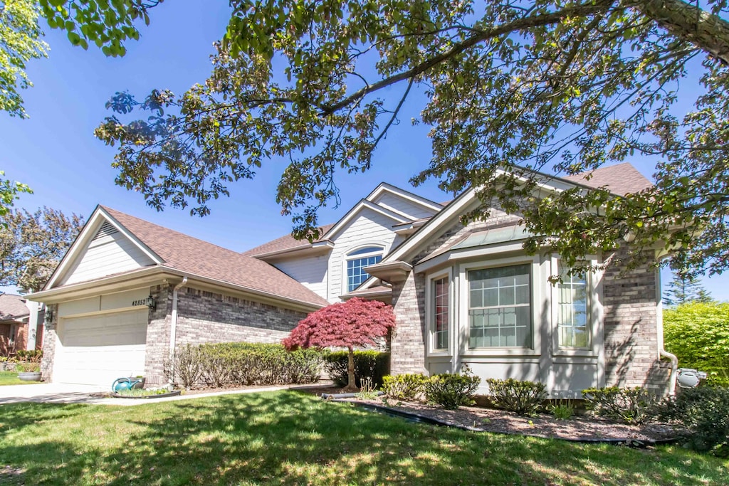42852 Sandstone Dr, Novi, MI 48377 - view of front of home with brick siding, a garage, and a front lawn