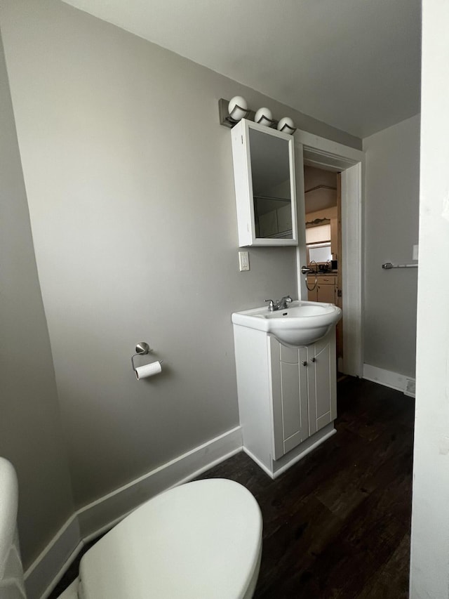 939 Baraga St NE, Grand Rapids, MI 49503 - bathroom with wood finished floors, vanity, toilet, and baseboards