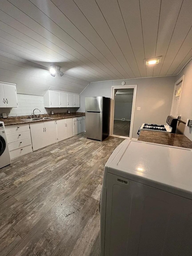 939 Baraga St NE, Grand Rapids, MI 49503 - kitchen with freestanding refrigerator, washer / dryer, dark wood finished floors, dark countertops, and white cabinetry