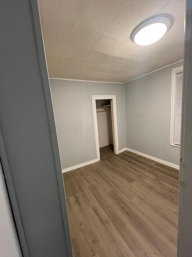 939 Baraga St NE, Grand Rapids, MI 49503 - unfurnished bedroom featuring wood finished floors, baseboards, a closet, and crown molding