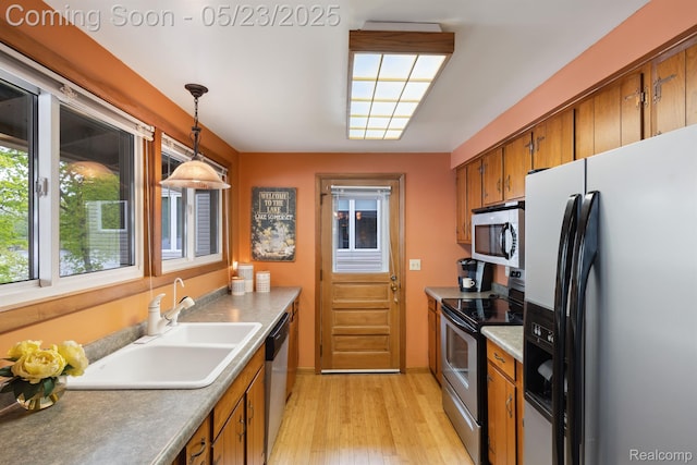 13953 Grandpoint Dr, Cement City, MI 49233 - kitchen with appliances with stainless steel finishes, brown cabinetry, a sink, light wood-style flooring, and hanging light fixtures