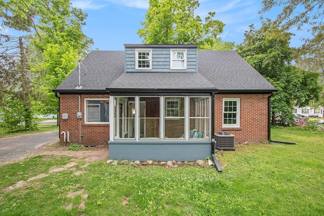 424 S Cass St, Berrien Springs, MI 49103 - view of front of home with central air condition unit, a front yard, brick siding, a sunroom, and roof with shingles