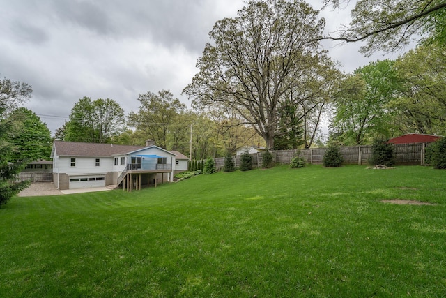 view of yard with an attached garage, stairway, a wooden deck, and view of wooded area
