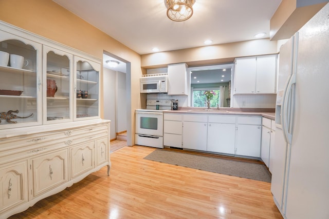 kitchen featuring white appliances, a sink, light wood finished floors, light countertops, and recessed lighting