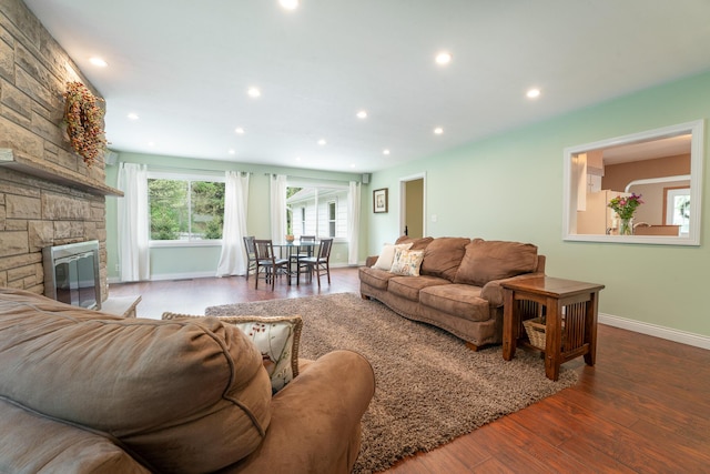 living area featuring wood finished floors, baseboards, recessed lighting, and a stone fireplace