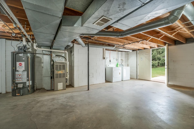 below grade area featuring water heater, washer and clothes dryer, heating unit, and concrete block wall