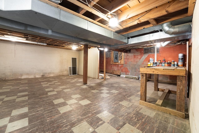 unfinished basement featuring tile patterned floors, electric panel, and a workshop area