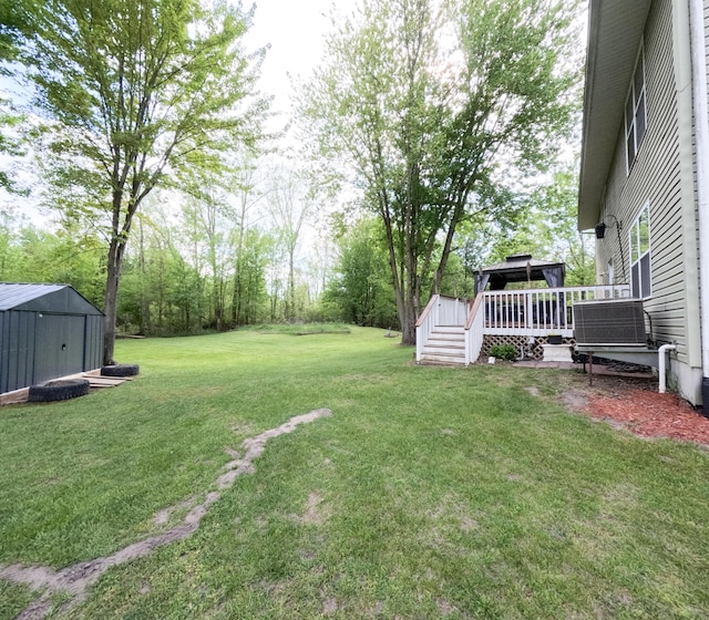 5734 108th Ave, Pullman, MI 49450 - view of green lawn featuring cooling unit, a deck, a storage unit, and an outbuilding