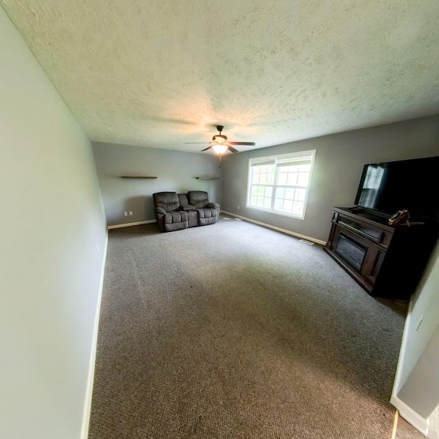 5734 108th Ave, Pullman, MI 49450 - unfurnished living room featuring a textured ceiling, a ceiling fan, a fireplace, baseboards, and carpet flooring