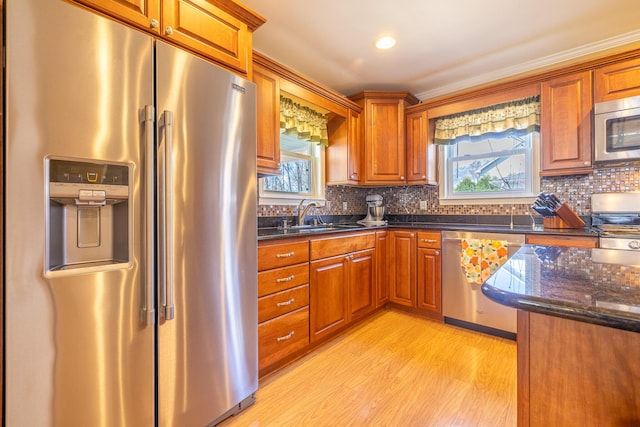1719 Center St, Carleton, MI 48117 - kitchen with appliances with stainless steel finishes, a sink, light wood-style flooring, brown cabinetry, and dark stone counters