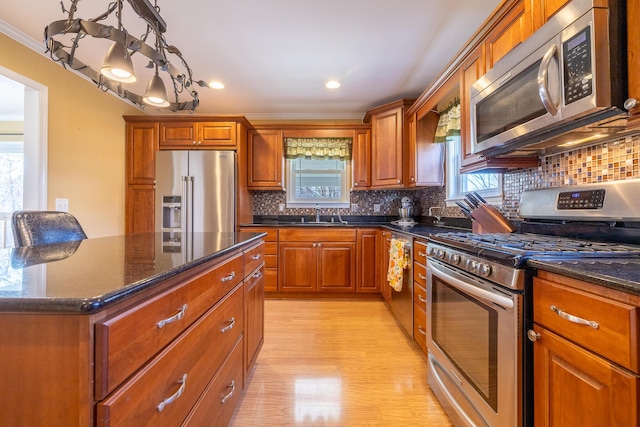 1719 Center St, Carleton, MI 48117 - kitchen featuring stainless steel appliances, light wood finished floors, brown cabinetry, backsplash, and ornamental molding