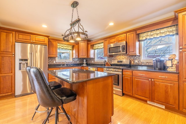1719 Center St, Carleton, MI 48117 - kitchen with appliances with stainless steel finishes, a center island, a breakfast bar, healthy amount of natural light, and crown molding