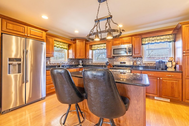 1719 Center St, Carleton, MI 48117 - kitchen featuring appliances with stainless steel finishes, light wood-style flooring, a kitchen breakfast bar, backsplash, and crown molding