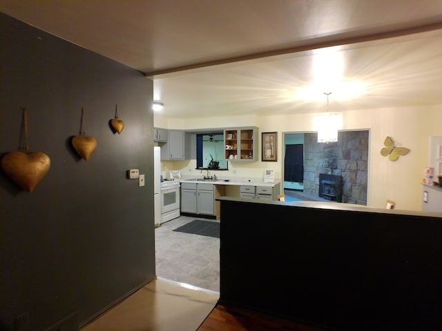 kitchen with white gas range, light countertops, a fireplace, a sink, and hanging light fixtures