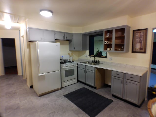 kitchen featuring white appliances, a sink, gray cabinets, and light countertops