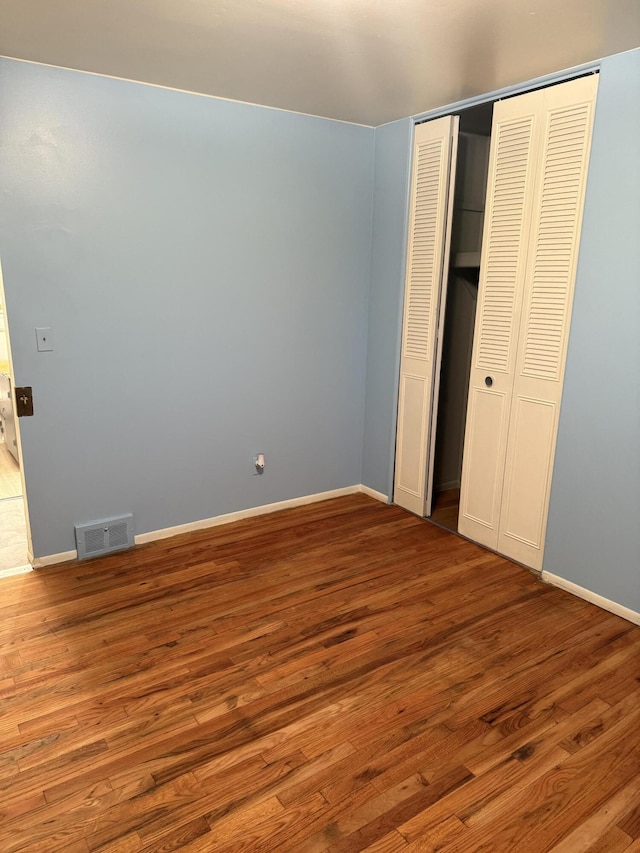 unfurnished bedroom featuring wood finished floors, a closet, and baseboards