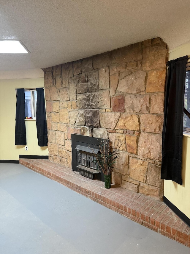 unfurnished living room featuring a textured ceiling, finished concrete floors, and baseboards