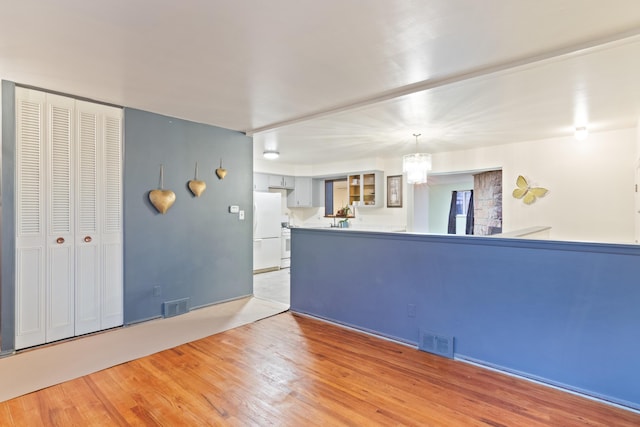 unfurnished living room featuring a chandelier and light wood-style flooring