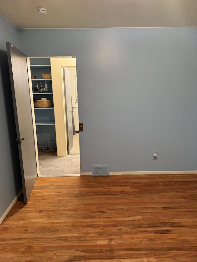 spare room with light wood finished floors, a smoke detector, and baseboards