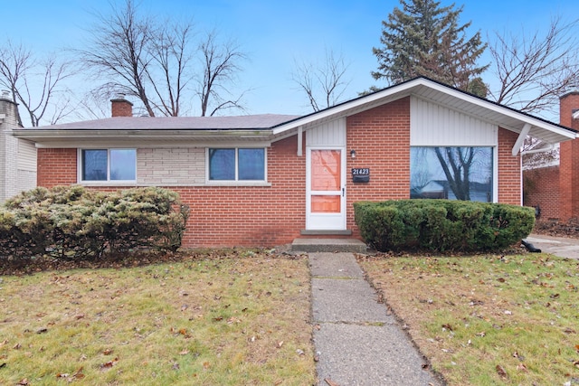 ranch-style home with a chimney, brick siding, and a front yard
