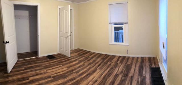 1402 N Ave NE, Grand Rapids, MI 49505 - unfurnished bedroom featuring dark wood-type flooring, a closet, and baseboards