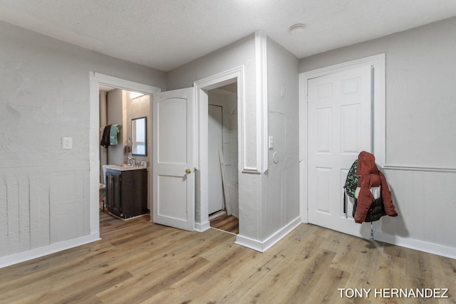 1402 N Ave NE, Grand Rapids, MI 49505 - unfurnished bedroom featuring light wood-style flooring, baseboards, a sink, and a textured ceiling