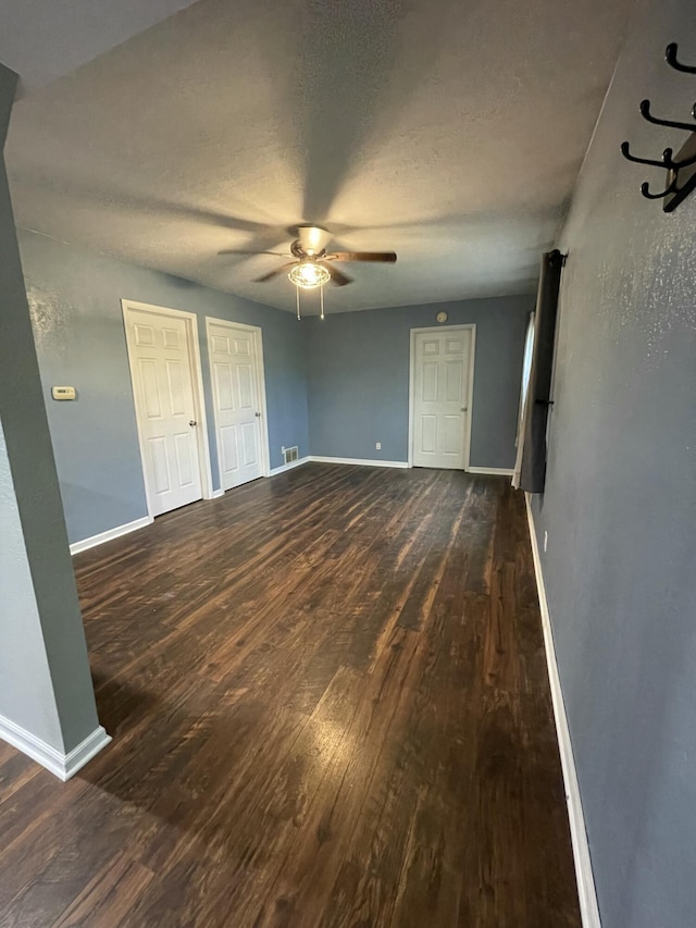 3800 W Hallett Rd, Hillsdale, MI 49242 - unfurnished bedroom featuring wood finished floors, baseboards, a ceiling fan, a textured ceiling, and two closets