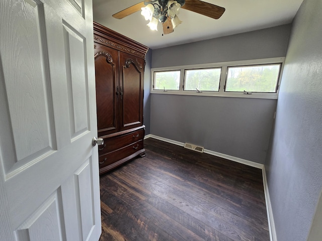 3800 W Hallett Rd, Hillsdale, MI 49242 - unfurnished bedroom with baseboards, dark wood-style flooring, and a ceiling fan