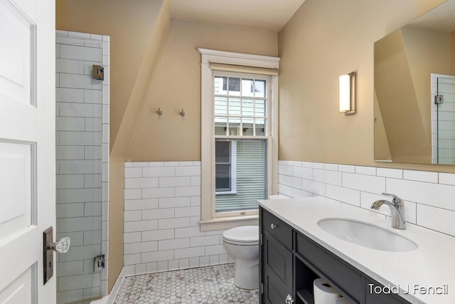 554 Madison Ave SE, Grand Rapids, MI 49503 - full bathroom with tile walls, tile patterned flooring, toilet, vanity, and a wainscoted wall