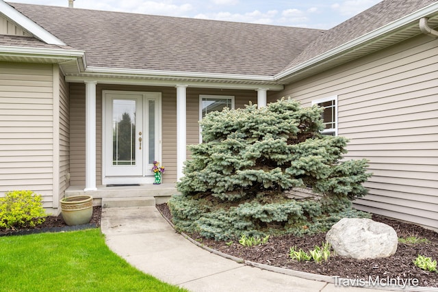 doorway to property featuring a shingled roof and a porch
