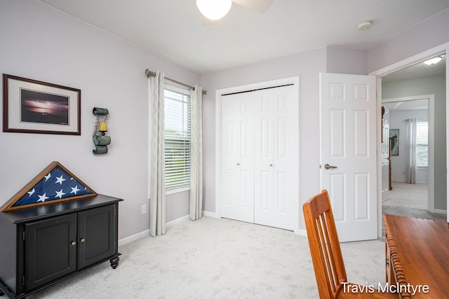 office area featuring light colored carpet, a ceiling fan, and baseboards