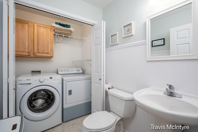bathroom featuring washer and dryer, a sink, wainscoting, and toilet