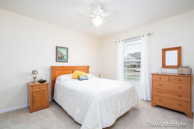 bedroom featuring light colored carpet, baseboards, and a ceiling fan