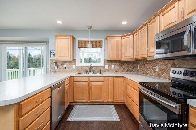 kitchen featuring stainless steel appliances, a sink, a peninsula, dark wood-style flooring, and light countertops