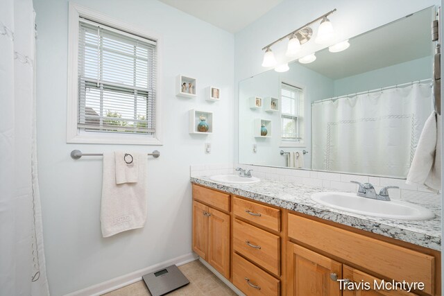 bathroom with double vanity, tile patterned flooring, and baseboards