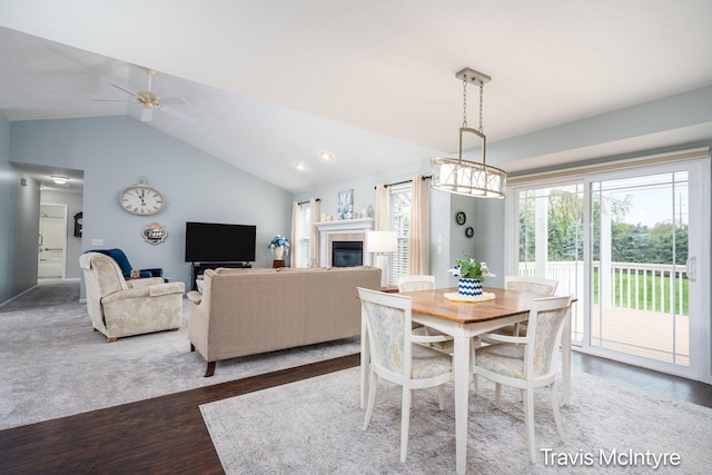 dining area featuring lofted ceiling, wood finished floors, ceiling fan, and a fireplace