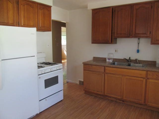 18478 Fox, Redford, MI 48240 - kitchen with white appliances, a sink, light wood finished floors, brown cabinetry, and baseboards