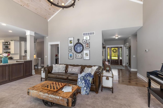 9510 Sparta Ave NW, Sparta, MI 49345 - living area featuring high vaulted ceiling, light carpet, baseboards, ornate columns, and a chandelier