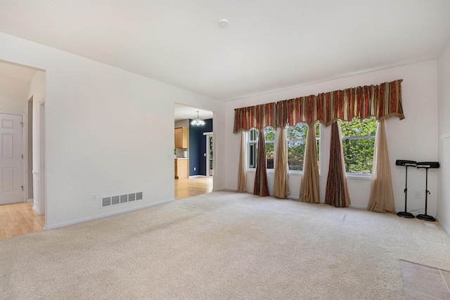 2570 Black Horse Ct NE, Grand Rapids, MI 49505 - empty room with light colored carpet, baseboards, and a chandelier