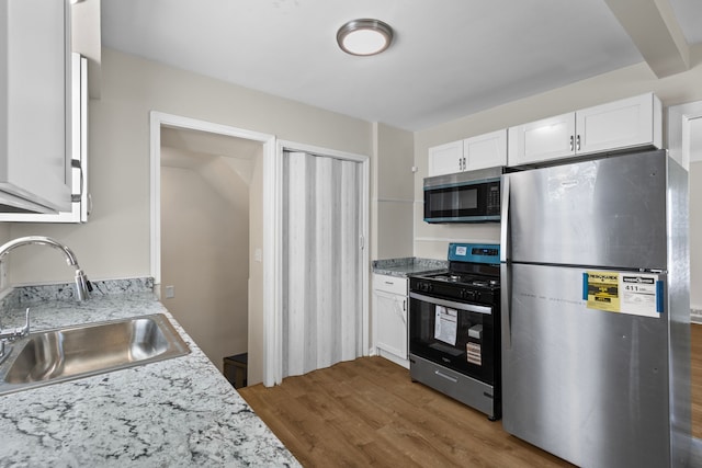 18750 Kingsville St, Harper Woods, MI 48225 - kitchen with appliances with stainless steel finishes, a sink, wood finished floors, white cabinetry, and light stone counters